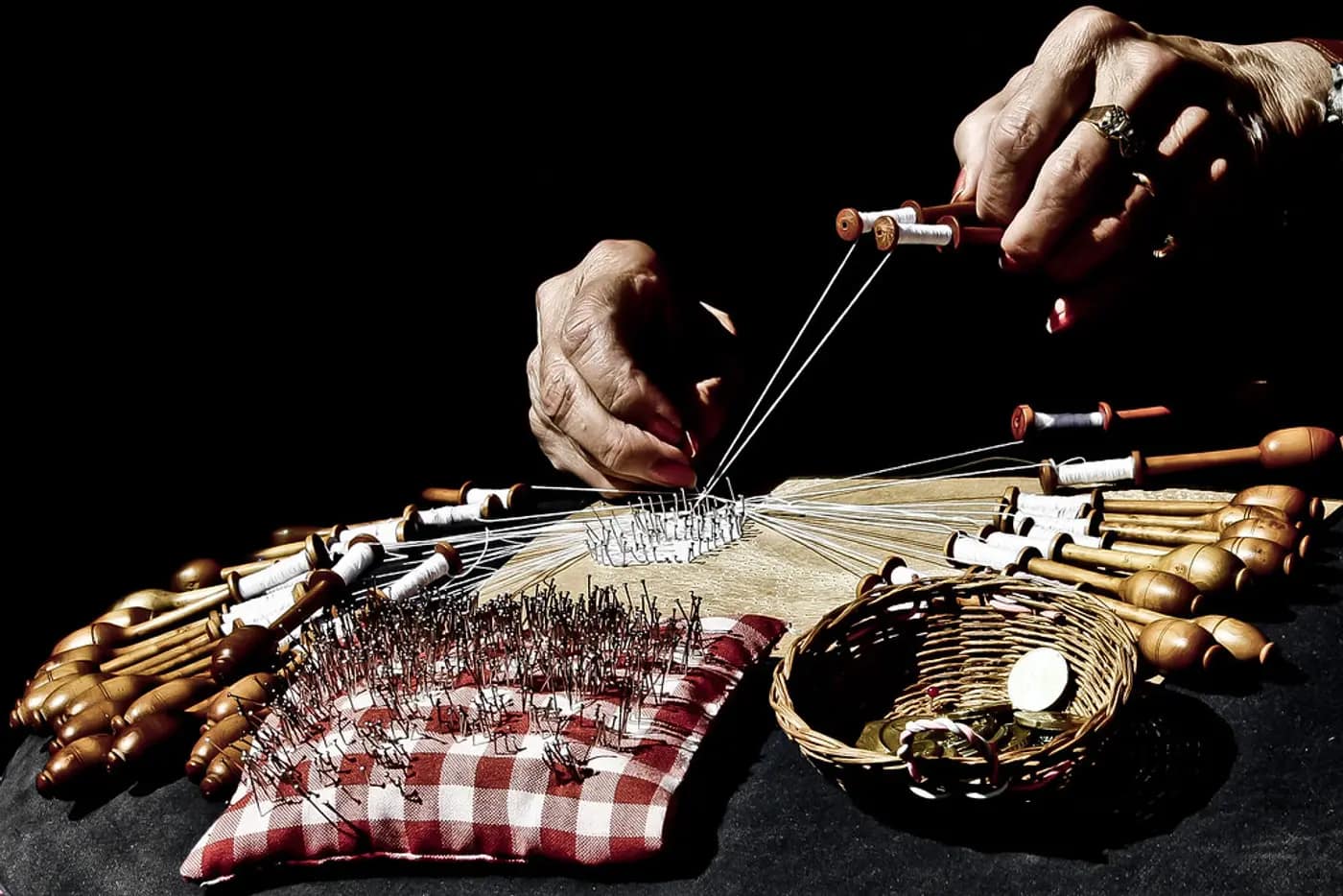 Wooden bobbins hanging from a pillow, each wound with a different weight of thread
