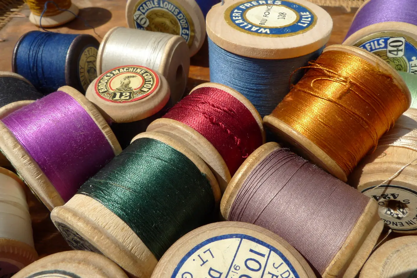 Spools of silk floss lined up by shade, from madder through to marigold